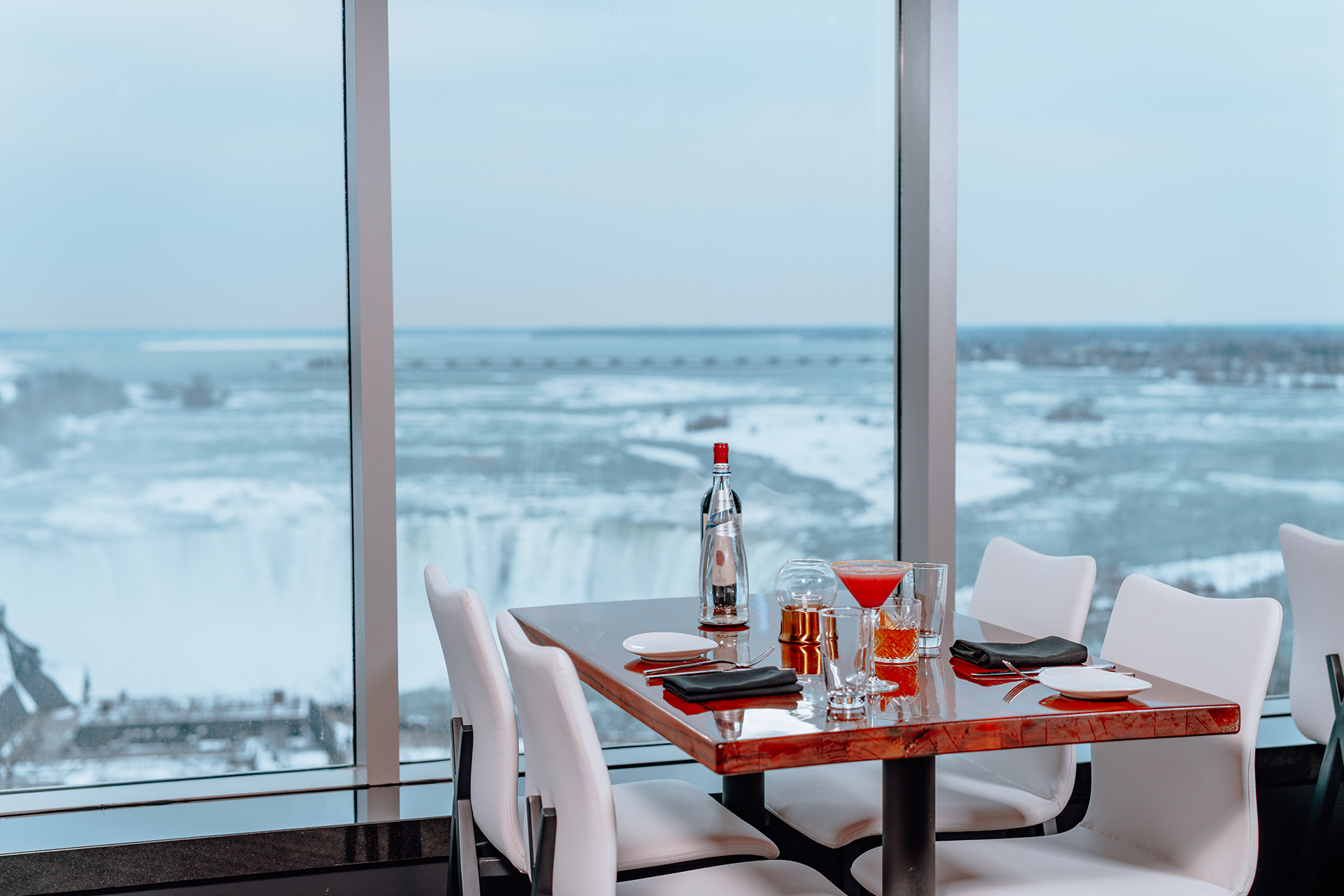 Fallsview dining table with cocktails by floor-to-ceiling windows