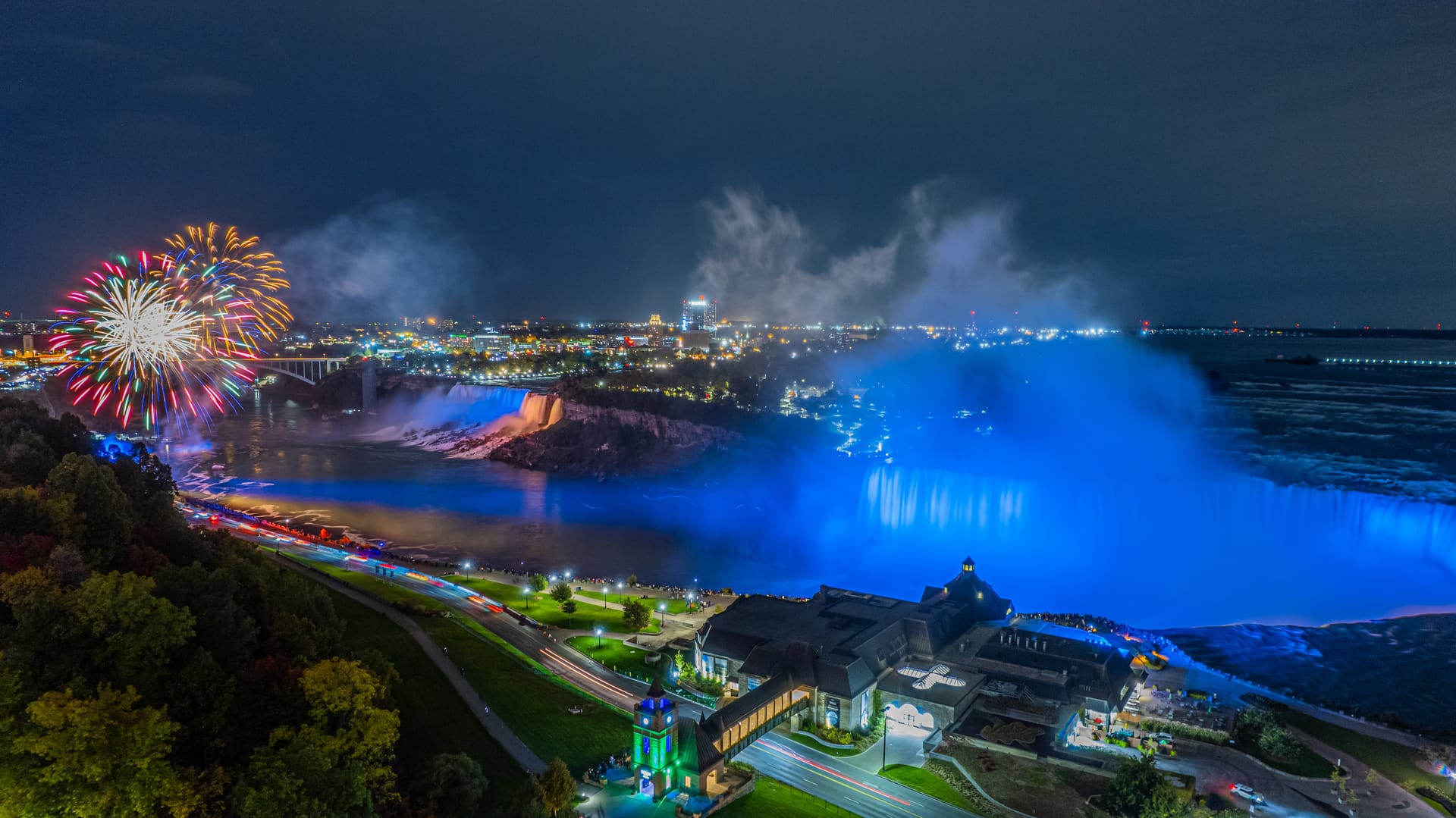 Nighttime fireworks over illuminated Niagara Falls