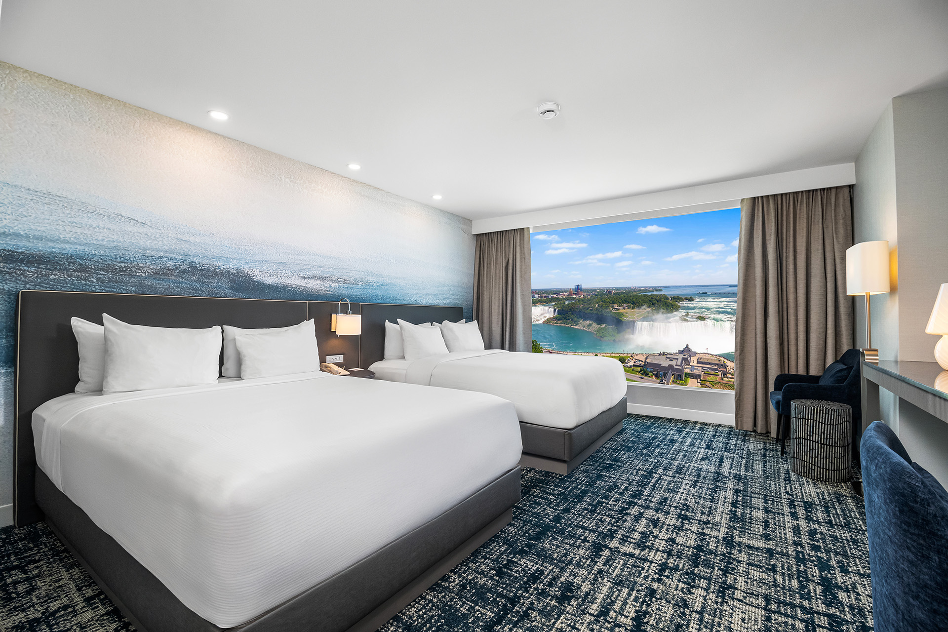 Double queen room with falls view window and blue-accent interior design