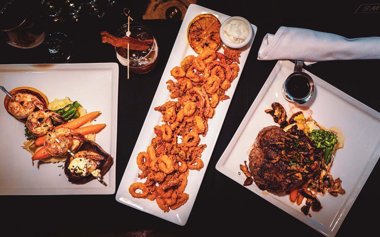 Plated steakhouse dishes with seafood and appetizers